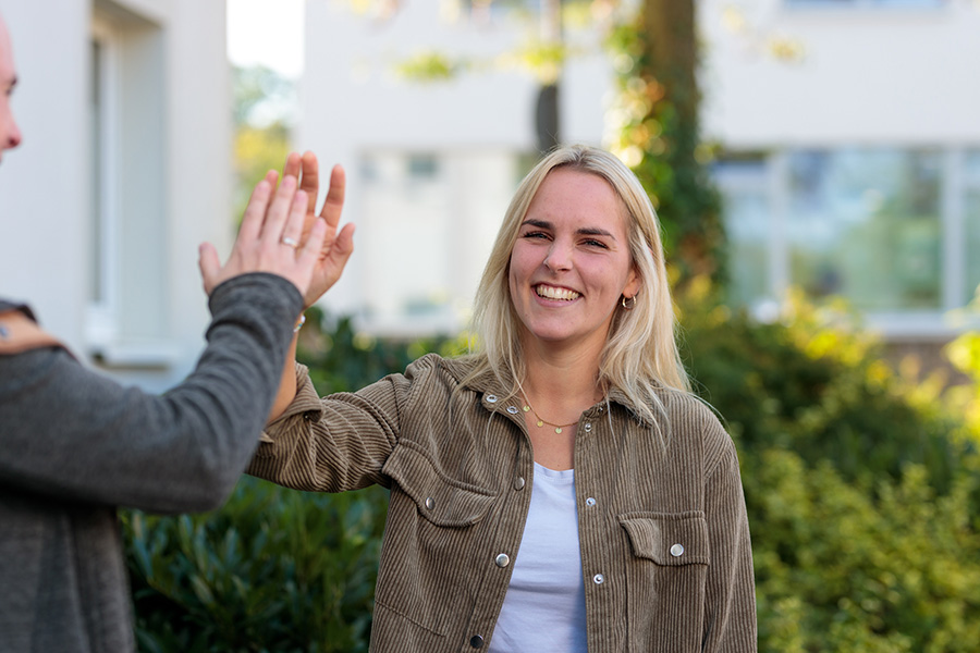 Sozialarbeiterin macht High Five, lächelt in die Kamera – Flexibilität und Work-Life-Balance beim Caritasverband Westeifel.