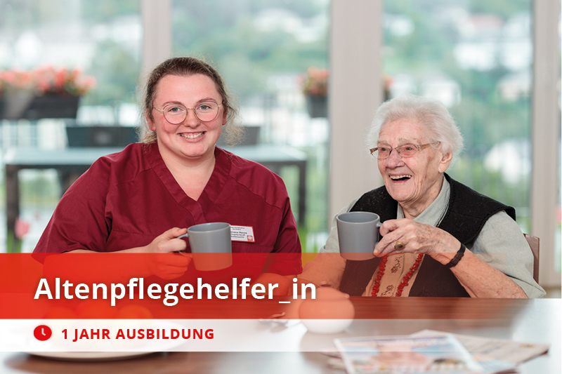 Altenpflegehelferin und Seniorin trinken Kaffee und lächeln – herzliche Pflegesituation beim Caritasverband Westeifel.